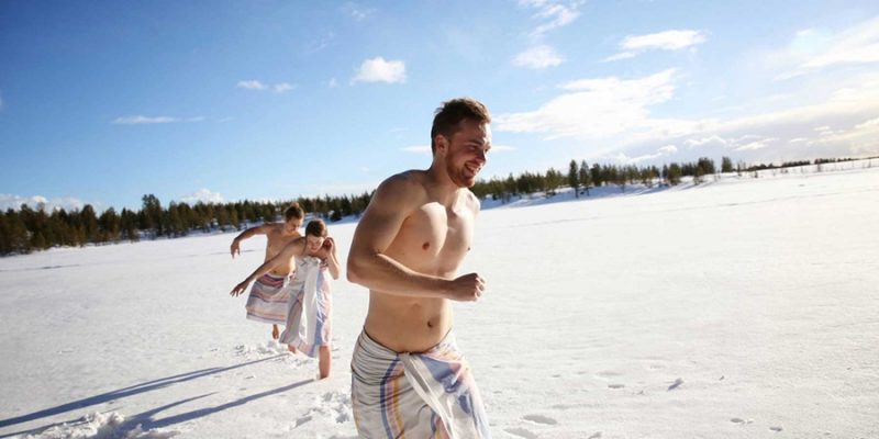 Gruppe rennt nach Sauna im Schnee in Skandinavien