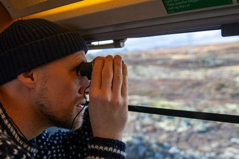 Mann-guckt-aus-dem-Zug-der-Dovrebanen-in-Norwegen-Fredrik Ahlsen Maverix-VisitNorway