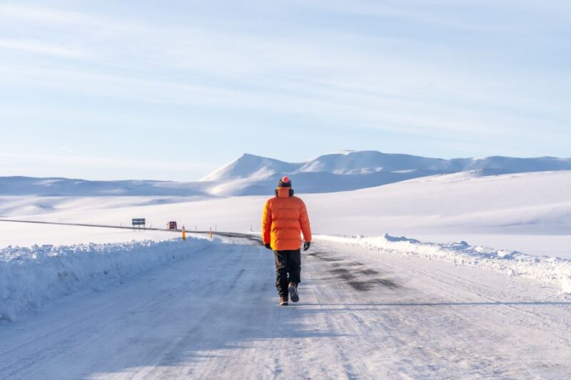 Mann-laeuft-auf-Strasse-in-Island-im-Winter-Reisen-mit-Nordic-der-Skandinavien-Spezialist